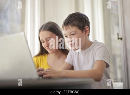 Brother and sister happily using a laptop together Stock Photo