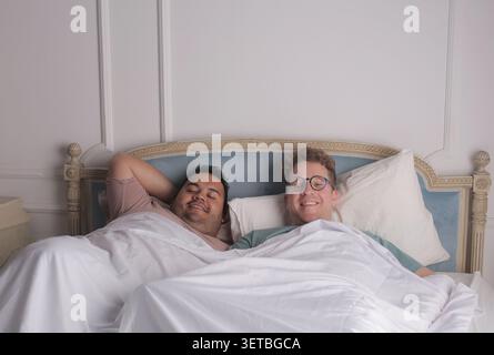 Happy male couple relaxing in bed together Stock Photo