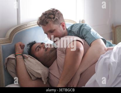 Loving gay couple cuddling in bed together in the morning Stock Photo
