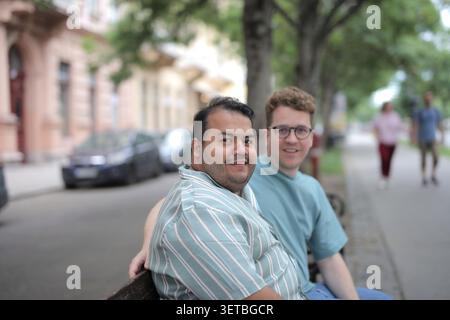 Happy male couple smiling on a city bench Stock Photo