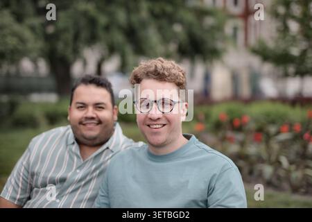 Two happy male friends sitting together in a park Stock Photo