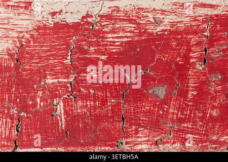 Distressed red paint cracking on an old concrete surface Stock Photo