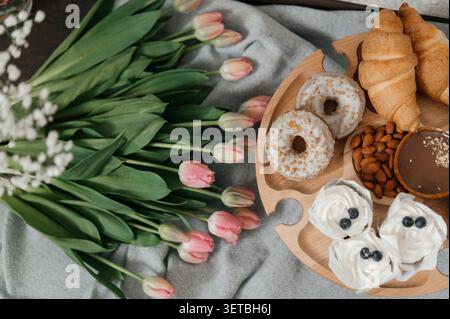A beautiful high-angle shot of a wooden serving tray filled with delicious treats, including glazed donuts, chocolate tarts, fresh croissants, Stock Photo
