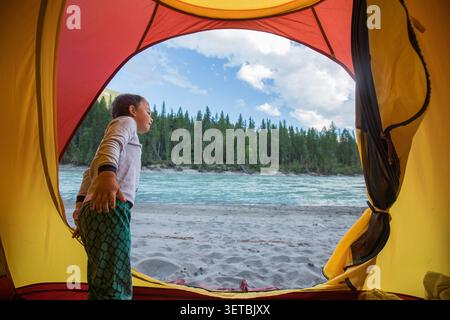 Curious boy camping by a river in the forest Stock Photo
