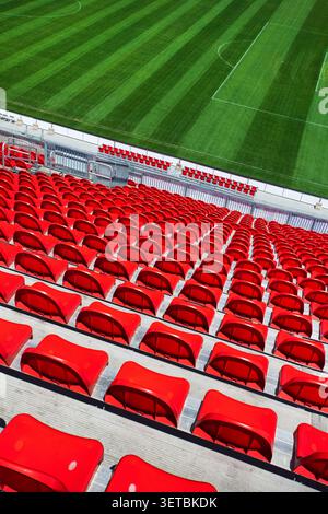 High angle view of empty red stadium seats overlooking a green sports Stock Photo