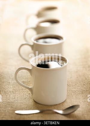 High angle view of four white coffee mugs lined up in a row on a Stock Photo