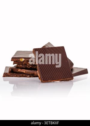 Broken dark chocolate squares stacked on white Stock Photo