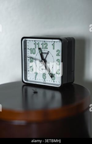 CASIO square alarm clock on polished wooden bedside table at 10 10 Stock Photo