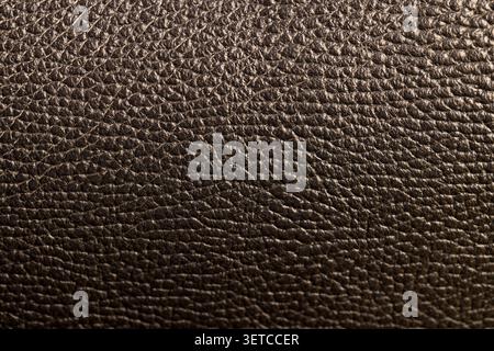 Leather of black color shines, dyed natural leather with a pronounced grainy relief under bright light with sharp details and organic texture in close Stock Photo