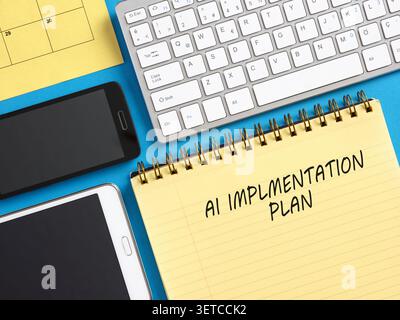 Yellow notepad showing AI implementation plan surrounded by smartphone, tablet, keyboard, and calendar Stock Photo