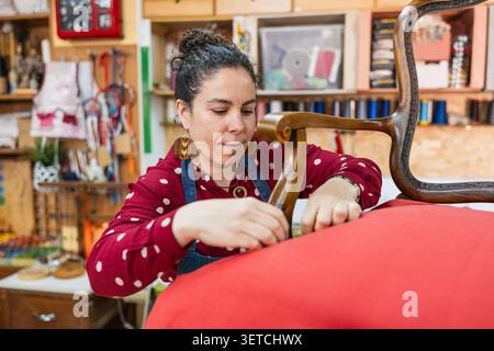 Woman doing upholstery work on an antique chair Stock Photo