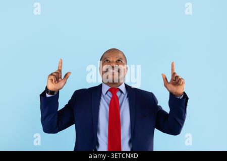 Mature African American businessman in suit pointing upward with both hands Stock Photo