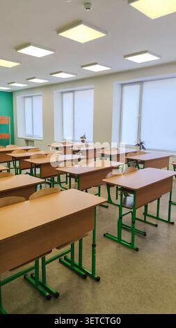 classroom with rows of desks and chairs in bright school interior with large windows. classroom empty without students, education environment, clean s Stock Photo