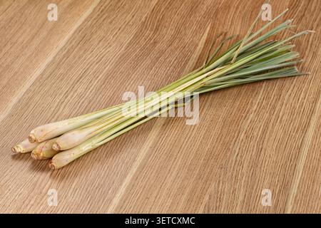 Fresh lemongrass stalks arranged diagonally on light wooden background. Green pale yellow hues. Natural lighting highlights texture freshness. Ideal f Stock Photo