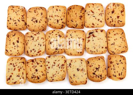 A heap of rectangular cranberry butter cookies with dried fruit bits scattered on a white background. Stock Photo