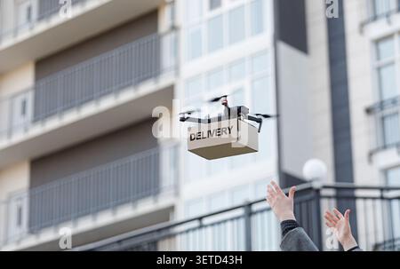 Flying drone carrying paper box on city blurred background Stock Photo