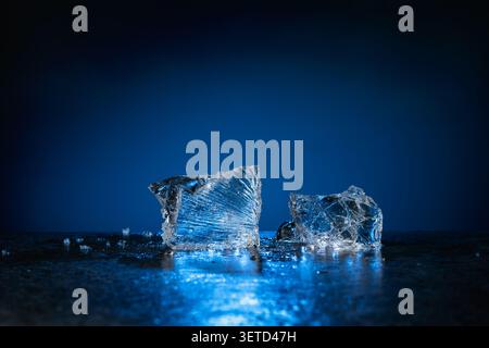 Broken ice with blue backlight on a dark background. Copy space. Stock Photo
