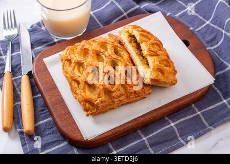 High angle view of golden curry chicken lattice pies served on a wooden cutting board with a glass of milk and cutlery. Stock Photo