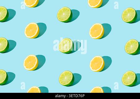 Summer fruit pattern made with green lime and yellow lemon slices on light blue background. Summer food and drink concept. Stock Photo