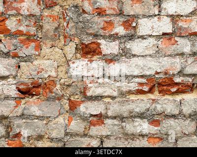 Close up of an old weathered brick wall with cracked plaster and exposed red bricks. Rustic grunge masonry texture background. Stock Photo
