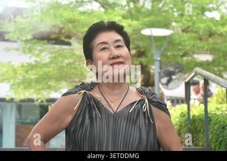 elder woman strong and healthy posing and smiling in community mall garden Stock Photo