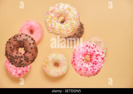Donuts on a warm beige background, lower part softly blurred, pastel food composition, top view, copy space present. Stock Photo