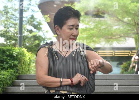 elder woman strong and healthy checking watch in community mall garden Stock Photo