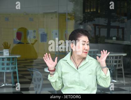 elder woman strong and healthy posing and smiling in community mall garden Stock Photo