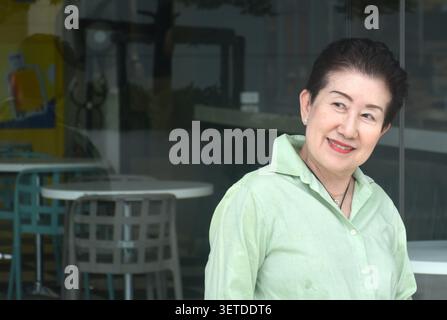 elder woman strong and healthy posing and smiling in community mall garden Stock Photo