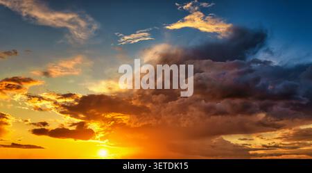A beautiful sunset sky with sunshine and dark, stormy clouds as a background or texture Stock Photo