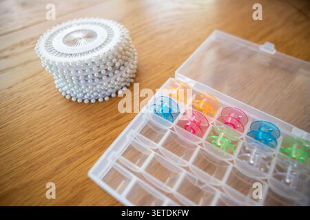Tailoring accessories with bobbins and dressmaker pins on home studio wooden table. Concept: creative hobby Stock Photo