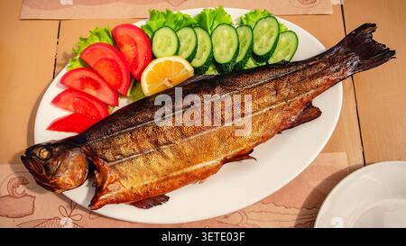 Grilled trout with vegetables on a wooden table. Stock Photo