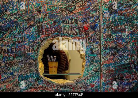 Graffiti Covered Wall with Viewing Hole and Creative Urban Messages Stock Photo