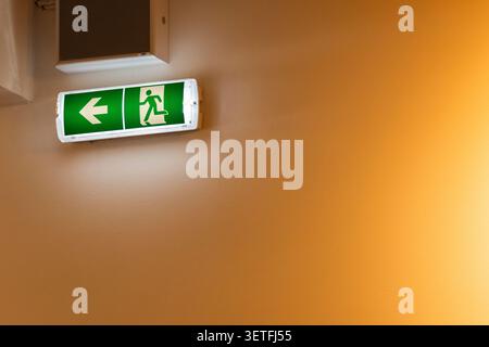 Illuminated green exit sign showing a running person and arrow, providing safety guidance Stock Photo