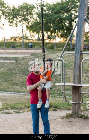 Father supporting son overcoming challenge on zipline Stock Photo