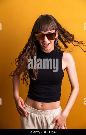 Young dancer with sunglasses expressing energy on yellow background Stock Photo