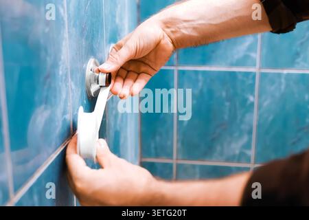 A handyman doing plumbing repair, wrapping teflon tape on a pipe thread for faucet replacement. Close-up of hands working on bathroom DIY home renovat Stock Photo