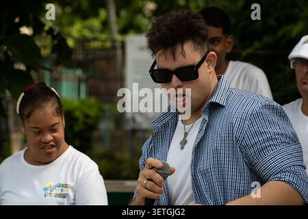 Young Cuban man with Down syndrome singing into a microphone during a unique social project performance in Ciego de Avila, Cuba Stock Photo