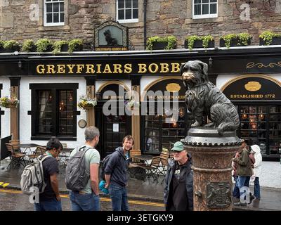Greyfriars Bobby dog statue outside the Greyfriars Bobby's Bar in Edinburgh, Scotland, with tourists and pub exterior. Stock Photo