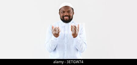 Smiling man in white shirt and cap praying with hands raised Stock Photo