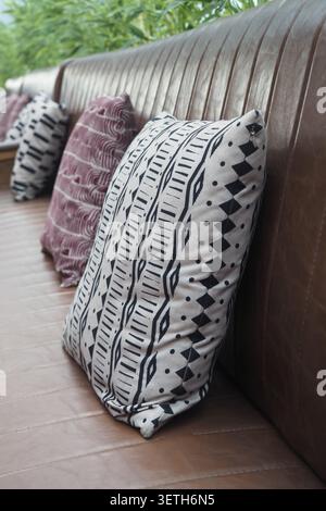 Colorful pillows on a brown leather sofa in a bright space Stock Photo