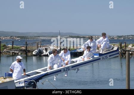 A blue and white AJS tournament boat with young competition participants in blue and white maritime clothing on the raised starting platform Tintaine Stock Photo