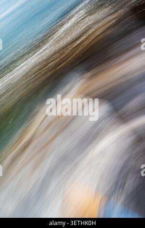 Abstract motion blur photograph of water creating diagonal streaks in blue, brown and white tones. The vertical image forms a textured background suit Stock Photo