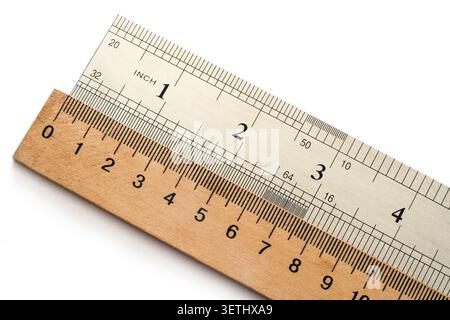 Metal and wooden rulers on a white background. The units of measurement are centimeters and inches. Stock Photo