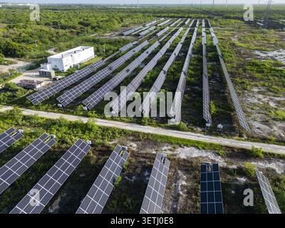 Aerial view of San Ignacio solar photovoltaic power plant with rows of solar panels, white maintenance building, and surrounding vegetation in Progres Stock Photo