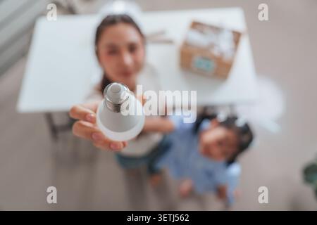 Asian woman holding LED light bulb for energy efficiency concept at home Stock Photo