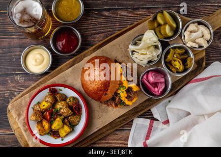 Slow cooked pulled rib beef burger with melted cheese and sides Stock Photo