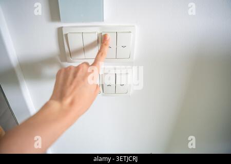 Hand pressing wall light switch in modern home interior. Energy saving and smart home control concept Stock Photo