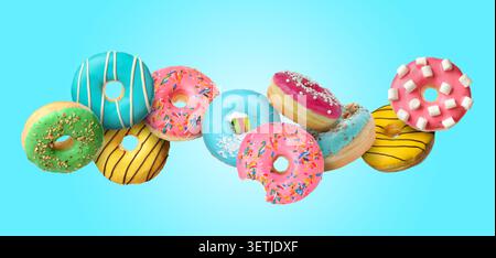 Yummy donuts covered with icing falling on light blue background Stock Photo