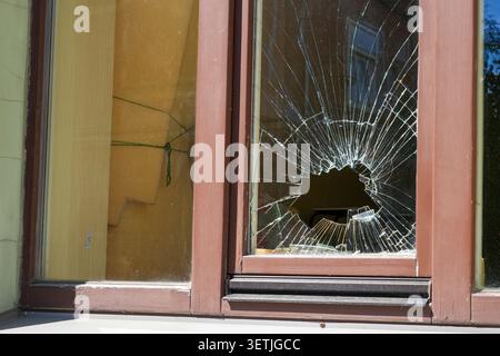 Damaged house window with shattered glass and impact hole. Concept of vandalism, burglary, accident, property damage and repair Stock Photo